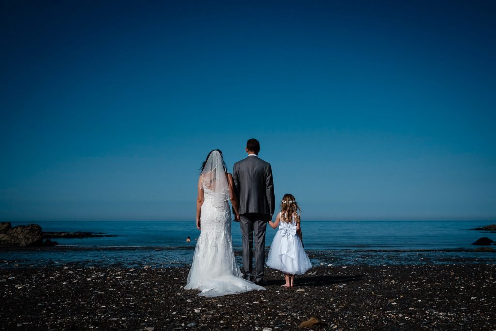 bride and groom and daughter on beach at sandy cove wedding